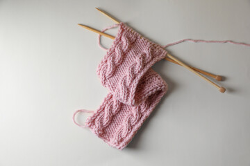 Pink knitting and needles on beige background, top view
