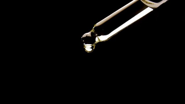 Cannabis oil in pipette drops on black background.