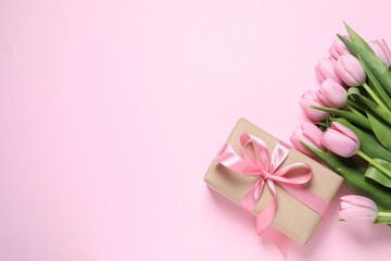 Beautiful gift box and bouquet of tulip flowers on pink background, flat lay. Space for text