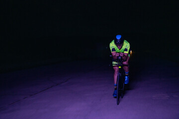 A triathlete rides his bike in the darkness of night, pushing himself to prepare for a marathon....