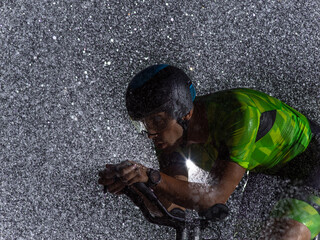 A triathlete braving the rain as he cycles through the night, preparing himself for the upcoming...