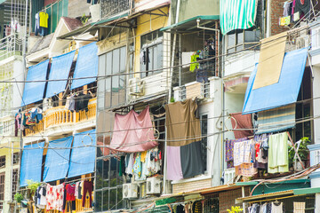 Looking up at the facade of an apartment block covered with cables, awnings and clothes drying at Hanoi in Vietnam - obrazy, fototapety, plakaty
