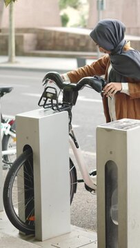 Muslim woman picks up an electric bike parked in the city