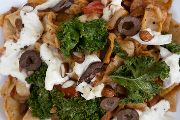 Pasta dish. Top view of a plate with pappardelle noodles, pesto, almonds, kale, burrata cheese and tomatoes.