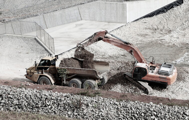 Excavator loading material to dump truck at open pit mining site