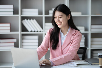 Young adorable Asian businesswoman working with laptop computer in her office room.