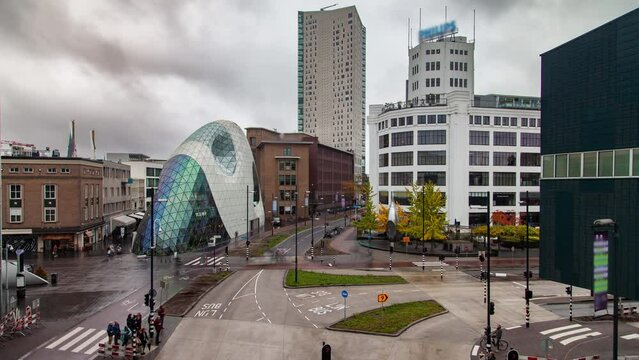 Timelapse of Eindhoven, Netherlands cityscape during autumn season. Showcases an urban scene with partly wet streets, daytime traffic, and modern buildings. Ideal for city life and travel scenes.