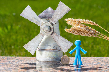 Ears of ripe wheat, a symbolic windmill, figurine of a man and a coin of denomination of 1 euro - obrazy, fototapety, plakaty