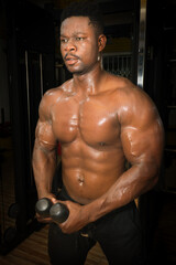 Fototapeta na wymiar A black muscular young man exercises in the gym for well-being