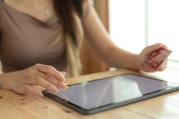 Woman holding a credit card and using tablet for online shopping