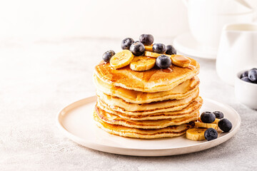 Pancakes with banana,  blueberries on white plate.