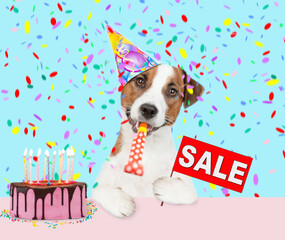 jack russell terrier puppy wearing sunglasses and party cap blows into party horn and showing signboard with labeled 