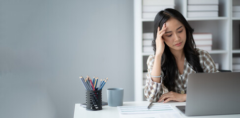 Stressed Asian businesswoman feeling upset about work and tired after a long day.