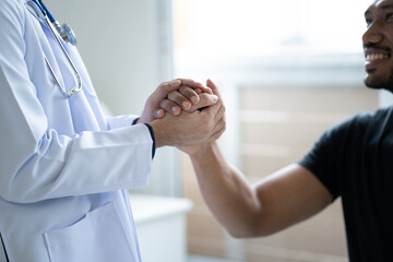 Close up view of friendly doctor hold patient hand in office during the visiting. giving hope and...