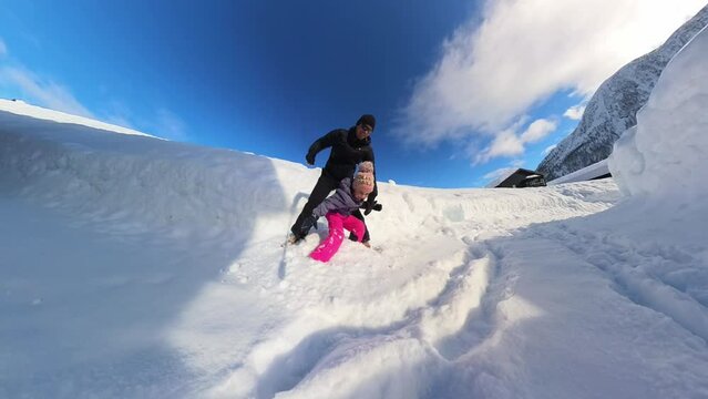 Father and daughter having great fun sliding down a snowy hil together in Myrkdalen winter wonderland Norway
