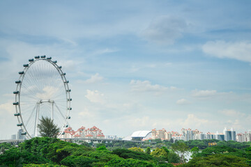 Singapore Ferris wheel with building and green park at Marina Barrage  is the park for outdoor activities .Beautiful architecture building exterior cityscape in Singapore city skyline with white cloud