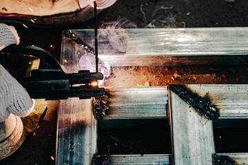 Industry worker wearing white glove and welding iron at work outdoor. Close-up hand tool for welding steel. Concept industrial using welding machine for construction.