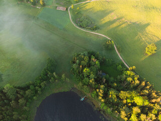 Rising Above the Beauty: Aerial View of Serene Green Pastures, Trees and Gravel Road During Sunrise with Drone in Northern Europe