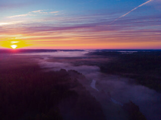 Drone's Eye View: Serene Sunrise Over Misty River and Woodland Landscape in Northern Europe