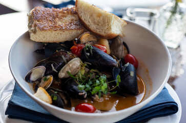 Seafood cioppino on the restaurant table with a view on marina