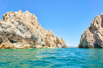 rocky mountains of los cabos, baja california sur, Mexico. Deep blue and emerald green Pacific Ocean in foreground. Los Cabos city in background.