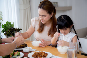 Happiness asian family mother and father and daughter eating food in kitchen together at home, parent and kid sitting dining in living room, bonding and relation, lifestyles and nutrition concept.