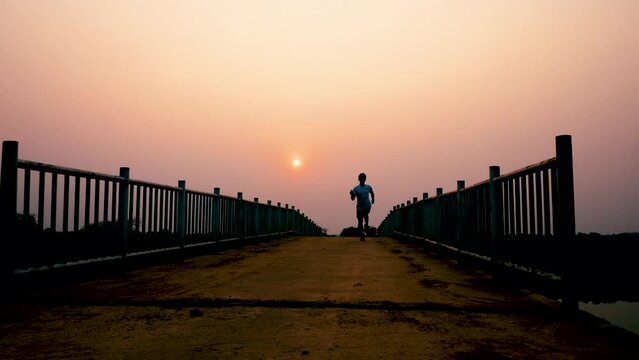Silhouette of young man running sprinting on road. Fit runner fitness runner during outdoor workout with sunset background. 4K