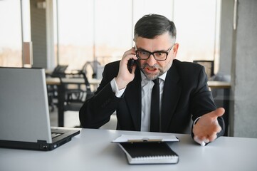 Angry manager throwing away his phone in his office