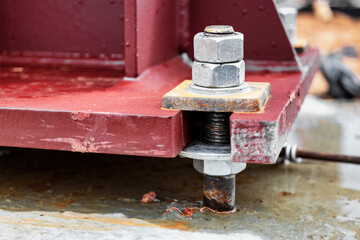 Installation of a metal column for an industrial building. Mounting bolts close-up. Connection of a structure with a reinforced concrete foundation. Anchor bolt.