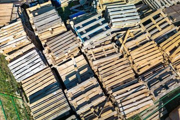 Empty wooden pallets stacked on construction site. Storage area for used pallets. Recycling of materials. View from above.