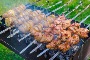 An BBQ grill is used for grilling kebabs and potatoes with bacon on skewer