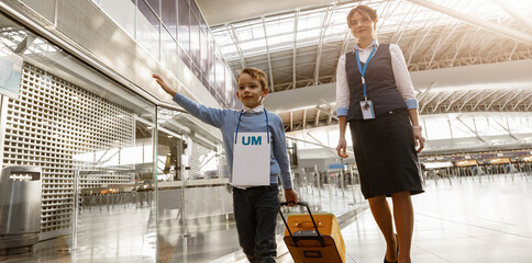 Female airport worker helps a little boy to find correct gate for boarding at the airport