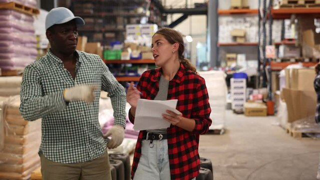 African american male and european female employees working at the warehouse