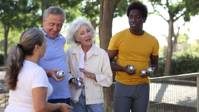 Portrait of friendly mature couples playing petanque at leisure