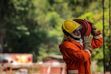 A firefighter carries a fire hose on his shoulder and a fire truck in the background, Copy space.