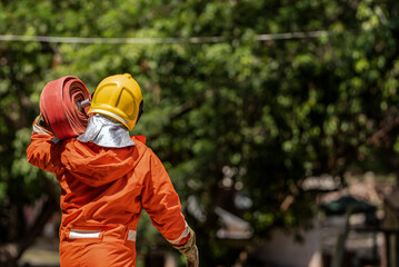 With synchronized movements, the firefighters carry the coiled fire hoses over their shoulders...