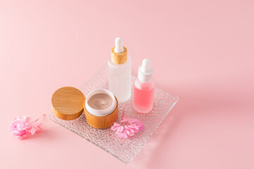 Obraz na płótnie Canvas body scrub in an open bamboo jar and two cosmetics in matte white bottles with a dropper for natural face and body skin care. Pink background.