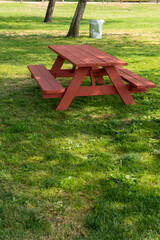 Picnic area with red table, trees and trash can in the park