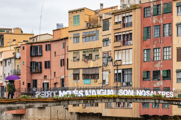 Girona, Spain - May 13th, 2023: TEMPS DE FLORS - Flower Time. Princess bridge with views of the Cathedral and the colorful houses of Onyar river on a rainy day. Banner 