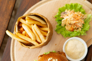 Chicken burger and french fries on a wooden cutting board