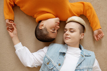 Top view of romantic loving lesbian woman couple lying face to face on floor