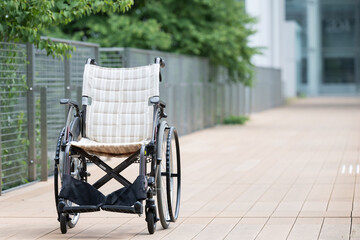 Unmanned wheelchair on outdoor walkway with copy space on the right side.