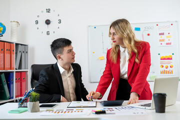 Two colleagues discussing business documents chart and graph at office