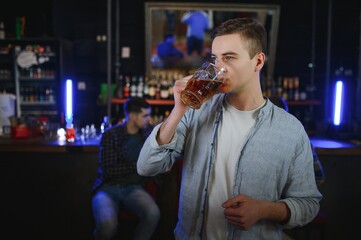 Night in bar. Portrait of cheerful men drinking beer at the bar