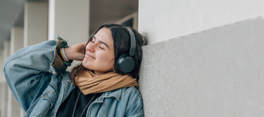 relaxed girl with headphones listening to music on the wall