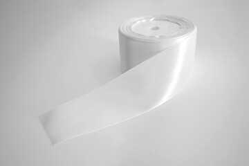 Roll of white textile ribbon. Mockup of roll from satin fabric tape on white background	