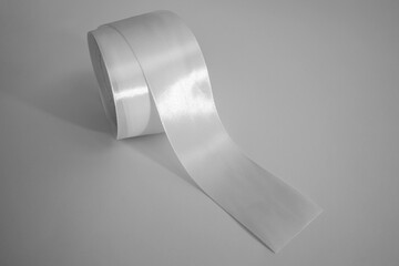 Roll of white textile ribbon. Mockup of roll from satin fabric tape on white background	