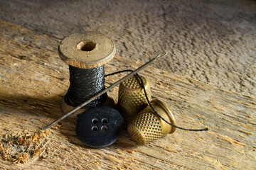 Antique sewing accessories. Tailor's accessories against the background of rough wood. Wooden spool...