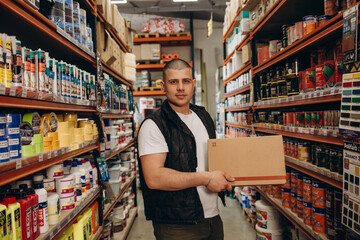 Caucasian consultant in uniform at hardware store. Male standing next to shelves with tools at store.
