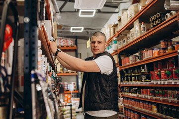 Caucasian consultant in uniform at hardware store. Male standing next to shelves with tools at...